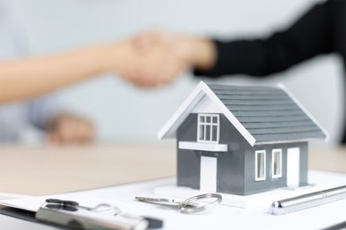 image two people shaking hands with a house belowthem depicting a fixed property transaction concluded